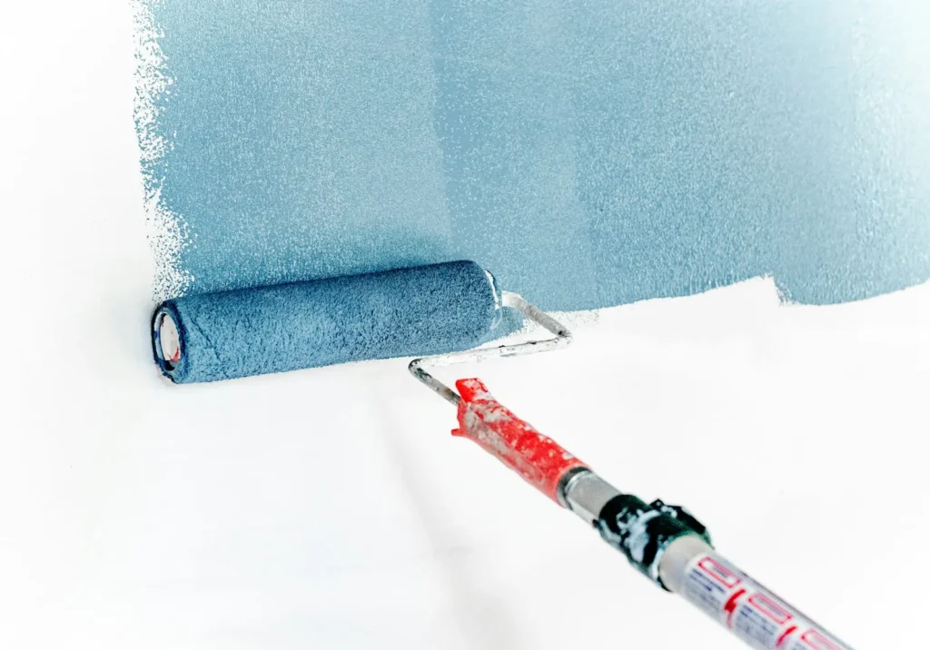 Painter rolling blue paint on a wall